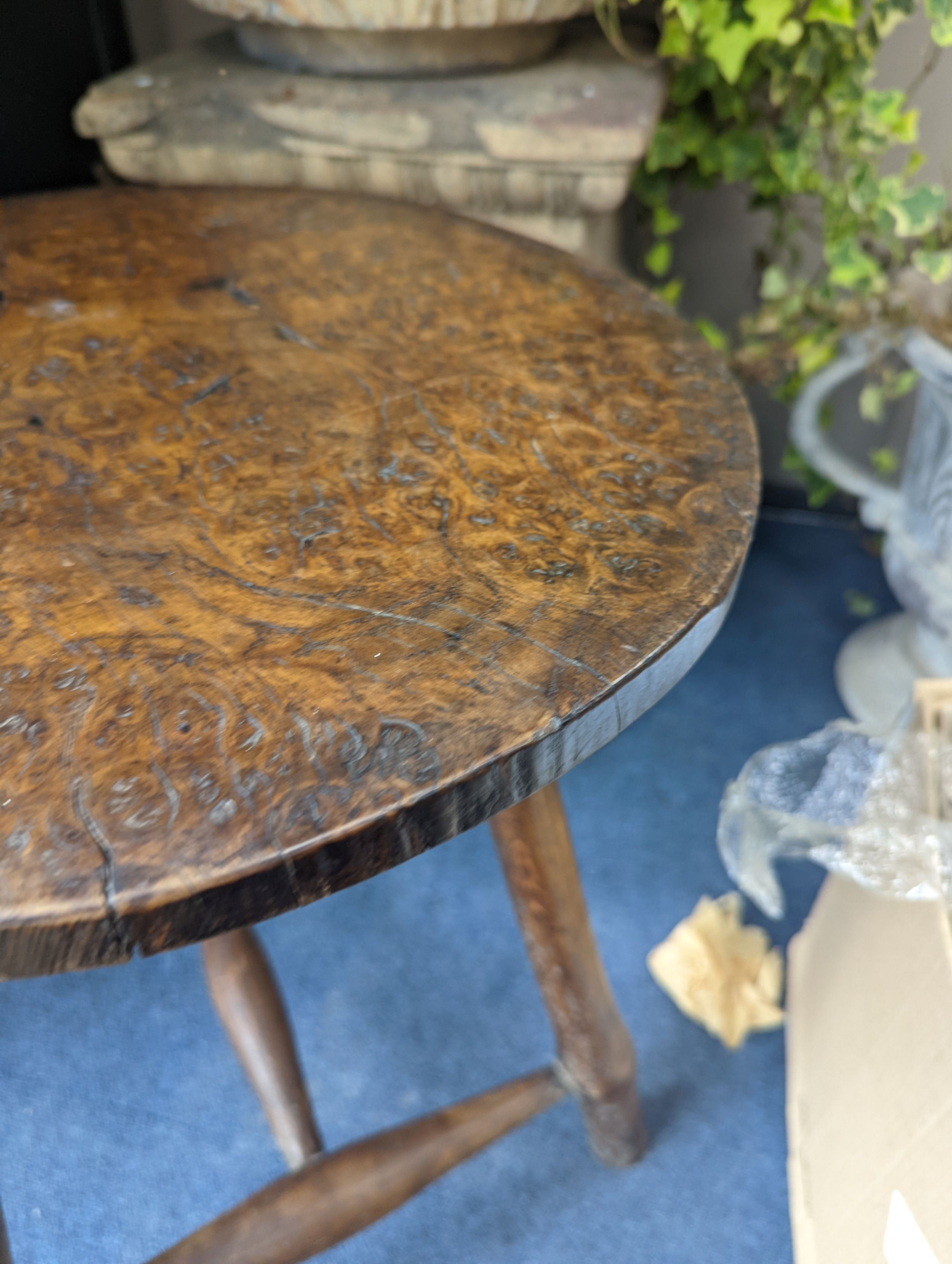 A circular burr elm and ash primitive cricket table with T shaped stretcher, diameter 44cm, height 61cm